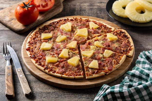 Hawaiian pizza with pineappleham and cheese on wooden table