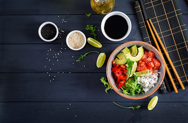 Hawaiian salmon fish poke bowl with rice, avocado, paprika, sesame seeds and lime. 