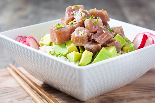 Photo hawaiian tuna poke bowl with avocado, radishes and sesame seeds on wooden table