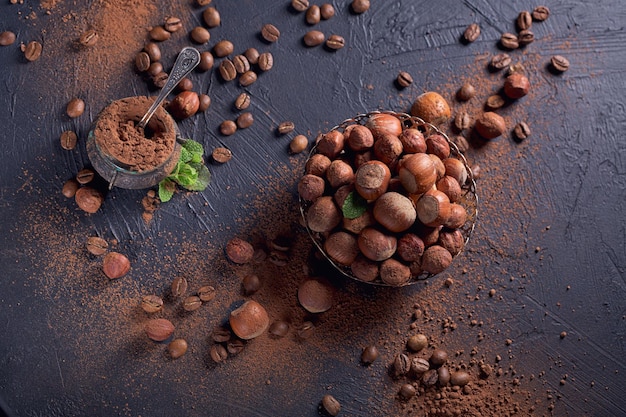 Hazelnoot, koffiebonen en cacaopoeder op donkere achtergrond. Ingrediënten voor het koken van zelfgemaakte chocoladesnoepjes. Zoetwaren en snoep concept