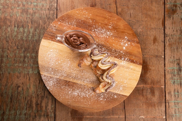 Hazelnootcrème croissantdessert met witte chocolade op houten bord en portie gesmolten chocolade op rustieke tafel in bovenaanzicht