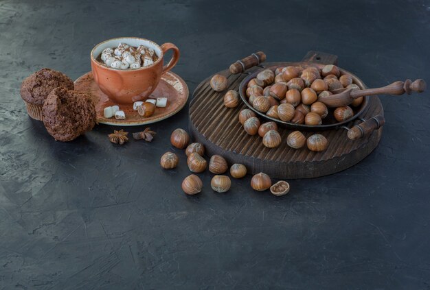 Hazelnoten, muffins en een kop warme chocolademelk met marshmallow dichtbij