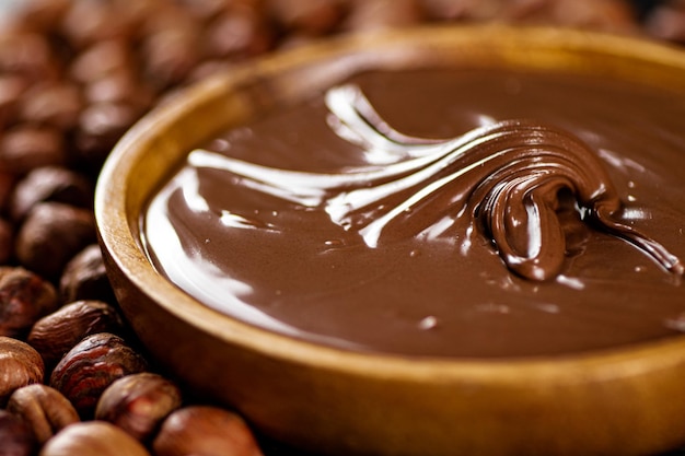 Hazelnut butter on a wooden plate with peeled hazelnuts