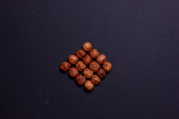 Hazelnut folded in the shape of a diamond Roasted hazelnuts on a black background