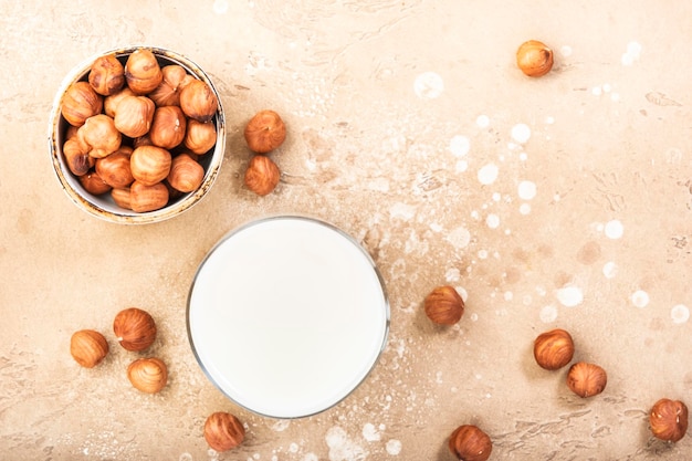 Hazelnut nut milk in glass beige table background Non dairy alternative vegan milk Healthy vegetarian diet food and drink