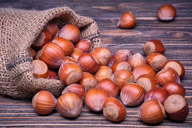 Hazelnuts in bag on old wooden background