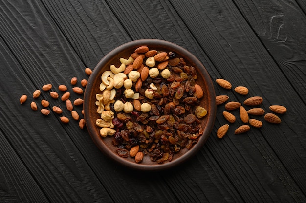 Hazelnuts cashews raisins almonds peanuts walnuts on a wooden black background