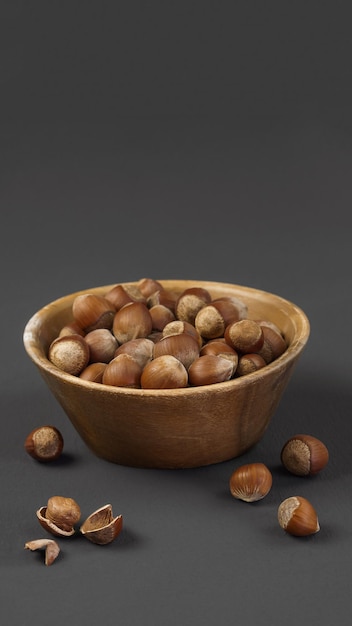 hazelnuts on a dark matte gray background closeup in a wooden plate closeup