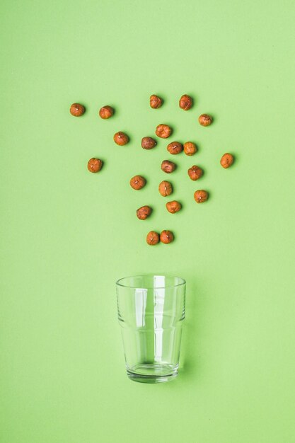 Hazelnuts and glass on green background. Health care, diet and nutrition concept.