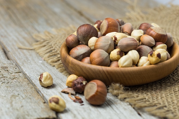 Hazelnuts and hazelnut in bowl on the wooden table.