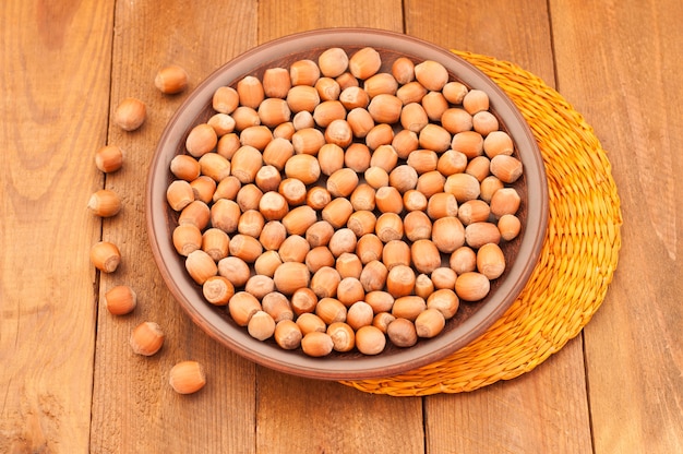 Hazelnuts on a plate and orange napkin on wooden background