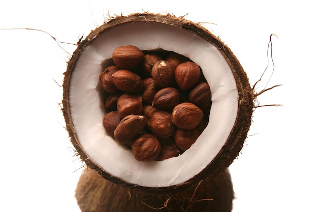 Hazelnuts in a split coconut on white background