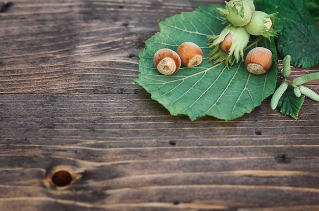 Hazelnuts with green leaves on a wooden surface