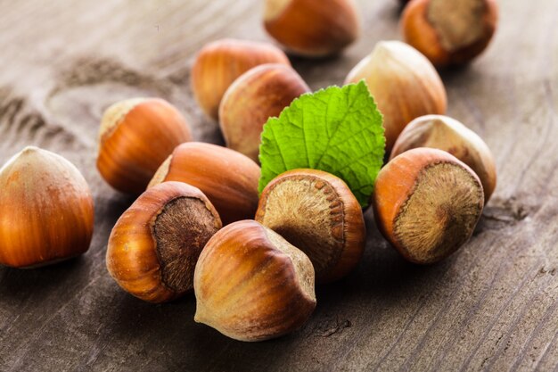 Nocciole con guscio e foglia verde sul tavolo di legno