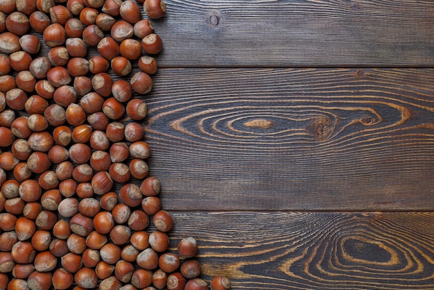 Hazelnuts with shells laid on brown wooden table surface