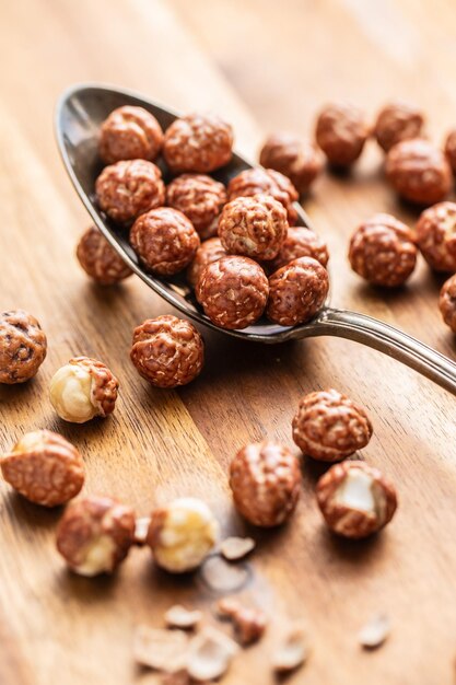 Foto nocciole con glassa di zucchero in cucchiaio su tavolo di legno