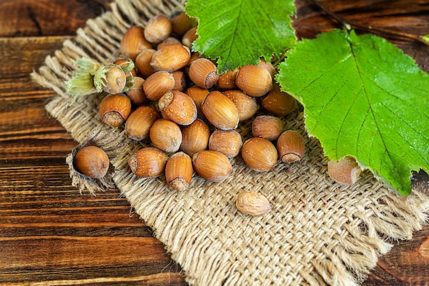 Nocciole su un fondo di legno con foglie verdi. contiene vitamine e minerali benefici.