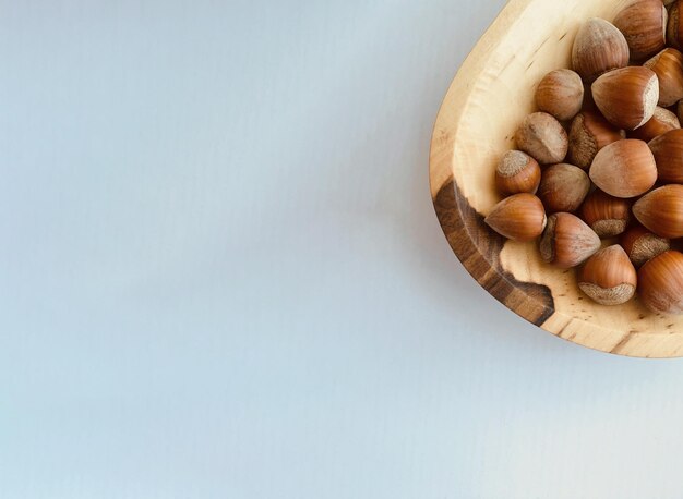 hazelnuts in a wooden plate on a white background copy space