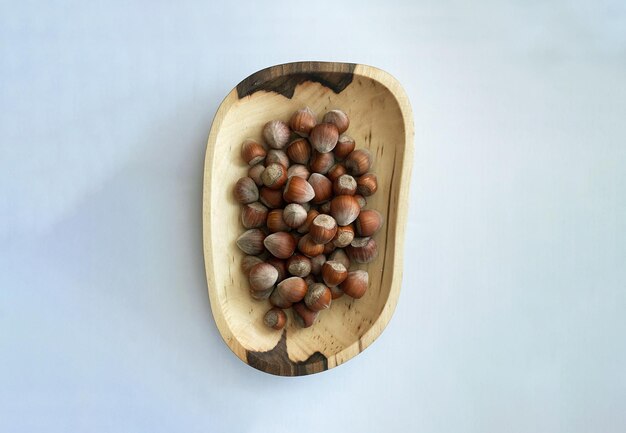 hazelnuts in a wooden plate on a white background