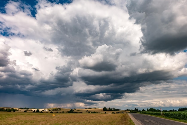 Hdr panorama on gravel road among fields in evening with awesome black clouds before storm