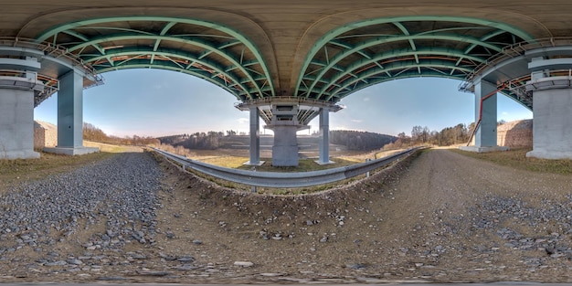 hdri 360 panorama on gravel road under steel frame construction of huge car bridge across river in equirectangular full seamless spherical projection VR AR content