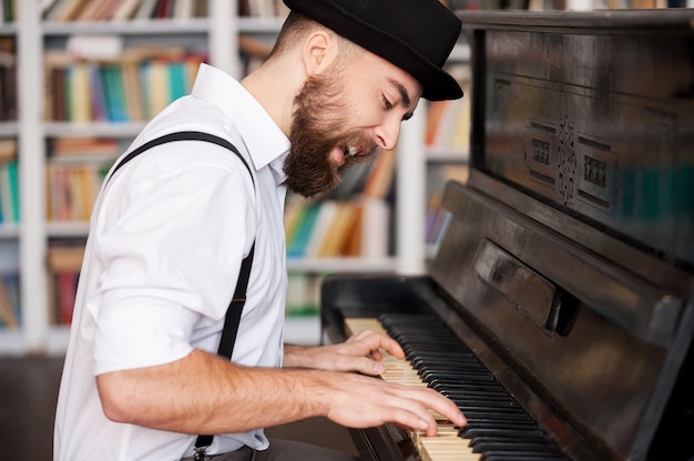 彼は創造的な魂を得ました。ピアノを弾いて歌うハンサムな若いひげを生やした男性