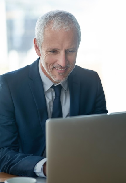 He has business all covered Cropped shot of a mature businessman working on a laptop in a modern office