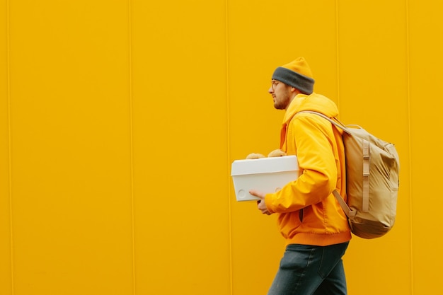 Photo he is carrying a white box and a bag of donuts