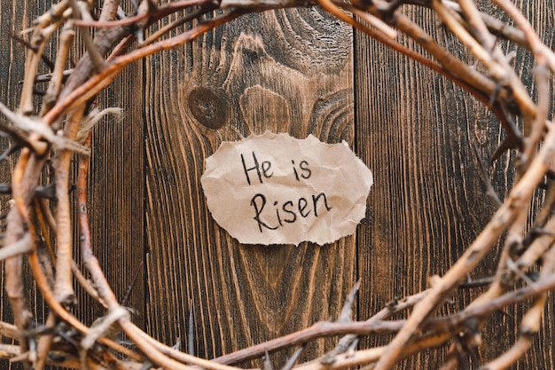 Photo he is risen jesus crown thorns and nails and cross on a wood background easter day