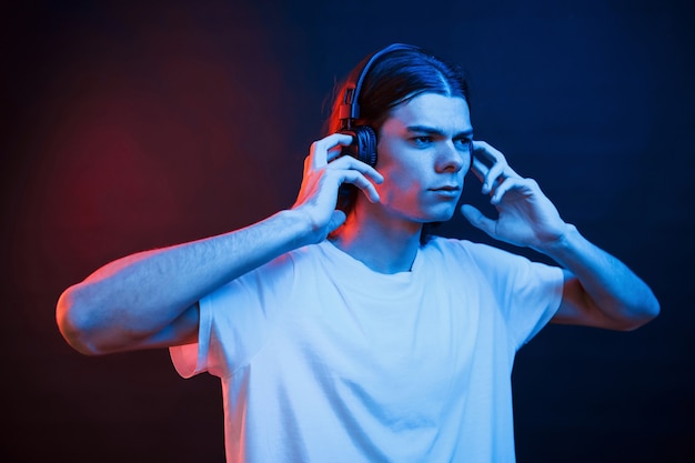 He listens carefully. Studio shot in dark studio with neon light. Portrait of serious man.