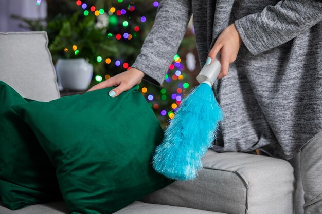 He picks up a green cushion from the sofa and cleans up the dust with a special brush christmas tree