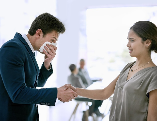 He really needs to go home and get better Cropped shot of a sick businessperson shaking hands with a colleague and sneezing in the office