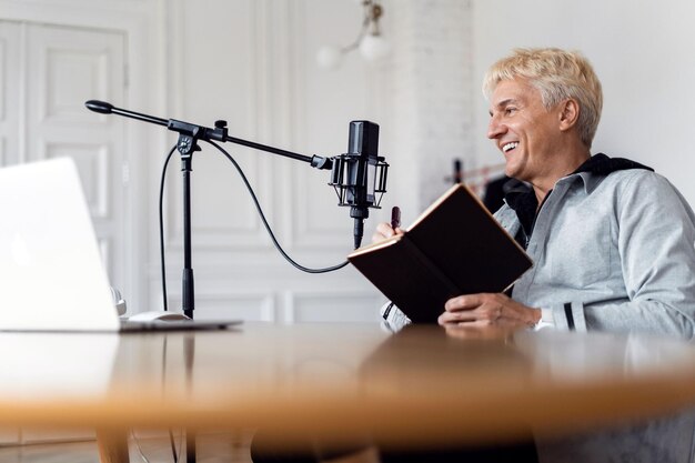 He speaks into the microphone about the news on the radio an\
adult grayhaired man is working a blogger\'s show with the\
participation of listeners a radio host communicates with\
people