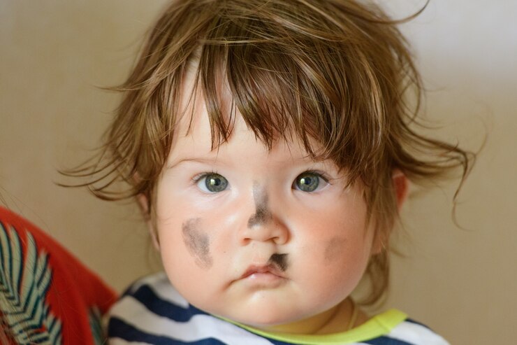 He stained face of a child. in the arms of the mother. The child is painted with watercolors. The child after applying the entire smeared, dirty face of the child