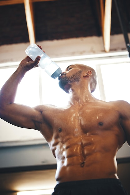 彼はジムで運動している間、水を飲んでいる筋肉質の若い男のローアングルショットで獣モードでいっぱいになりました