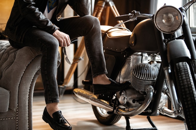 He will melt your heart. Handsome young man in leather jacket looking away while sitting on the stool