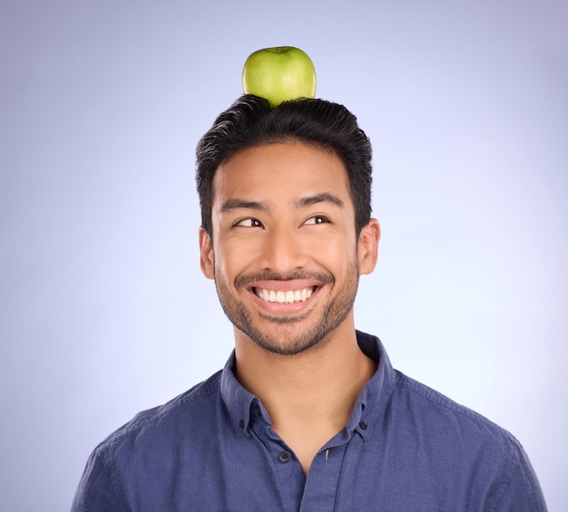 Head apple and Asian man with smile balance and healthy lifestyle against a grey studio background Male Japan and guy with fruit diet or thinking with happiness cheerful or joyful with wellness