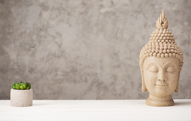 Head  Buddha and flower in concrete pot on gray background, copy  space. Meditation, Zen and Buddhism concept