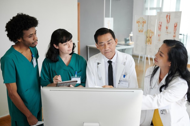 Head of clinic and his team gathered in front of computer