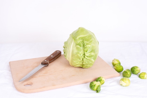 Head of fresh early cabbage on cutting board with knife and brussels sprouts