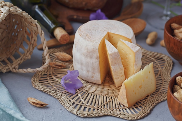 Голова свежего органического сыра подается с хлебом, орехами, белым вином и летними цветами. Концепция здорового и органического питания.