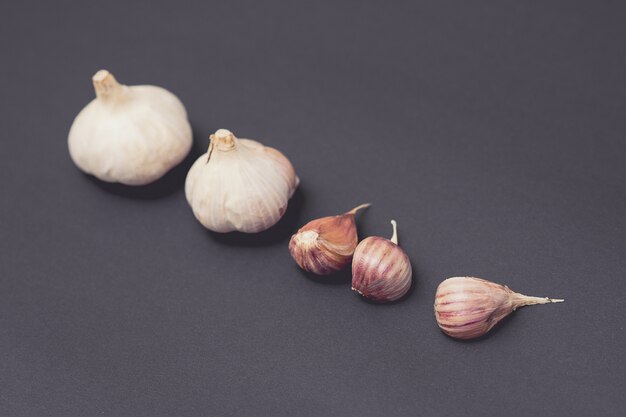 Head of garlic and garlic cloves on black surface.