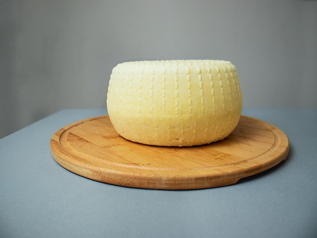 Head of hard or semi-hard cheese on a cutting board on a gray backgroundview from above