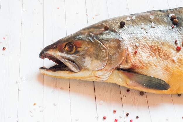 Head raw humpback fish with spices on a light table.