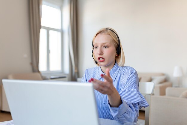 Head shot attractive friendly woman sitting at desk holding video call with friends at home Smiling young hotline specialist helping customers remotely at workplace