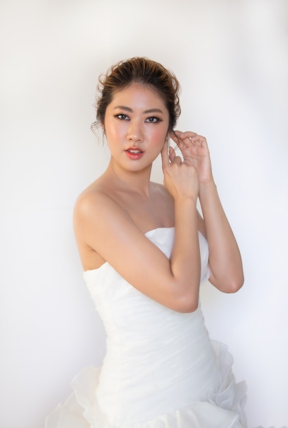 Head shot of beautiful attractive smiling woman in white wedding dress with bridal hair curl hairstyle.