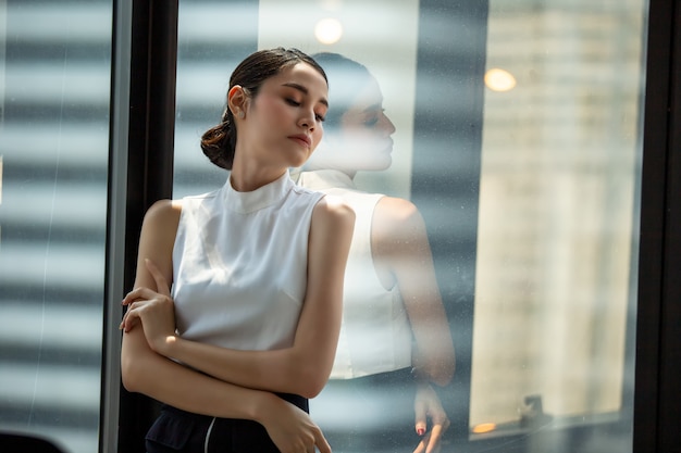 head shot of confident business women standing by window in office
