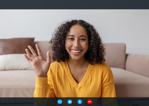 Head shot of happy young black woman waving at webcam greeting\
friend or teacher during remote chat