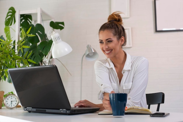 Colpo alla testa piacevole felice giovane donna freelance che lavora al computer a casa attraente imprenditrice