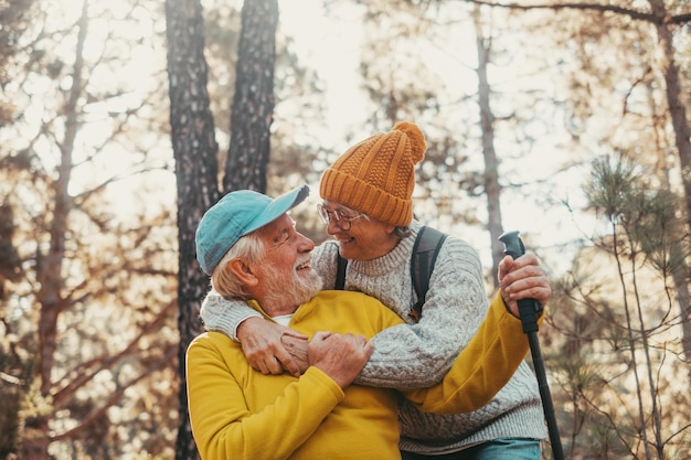 Head shot portrait close up of old people smiling and enjoying looking each other in the forest of mountain Cute couple of mature seniors in love feeling happy and taking care